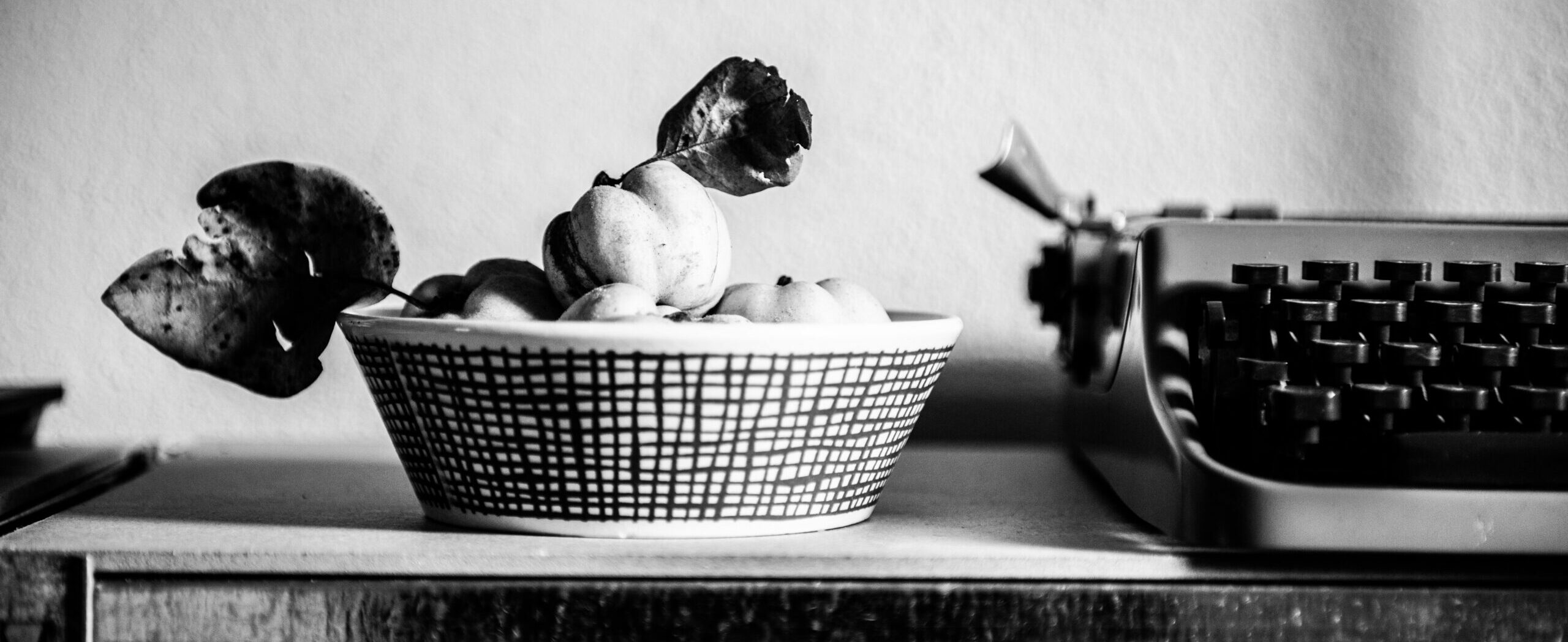 schwarz-weiß Bild mit Obstschale, in der Quitten liegen mit Schreibmaschine rechts daneben